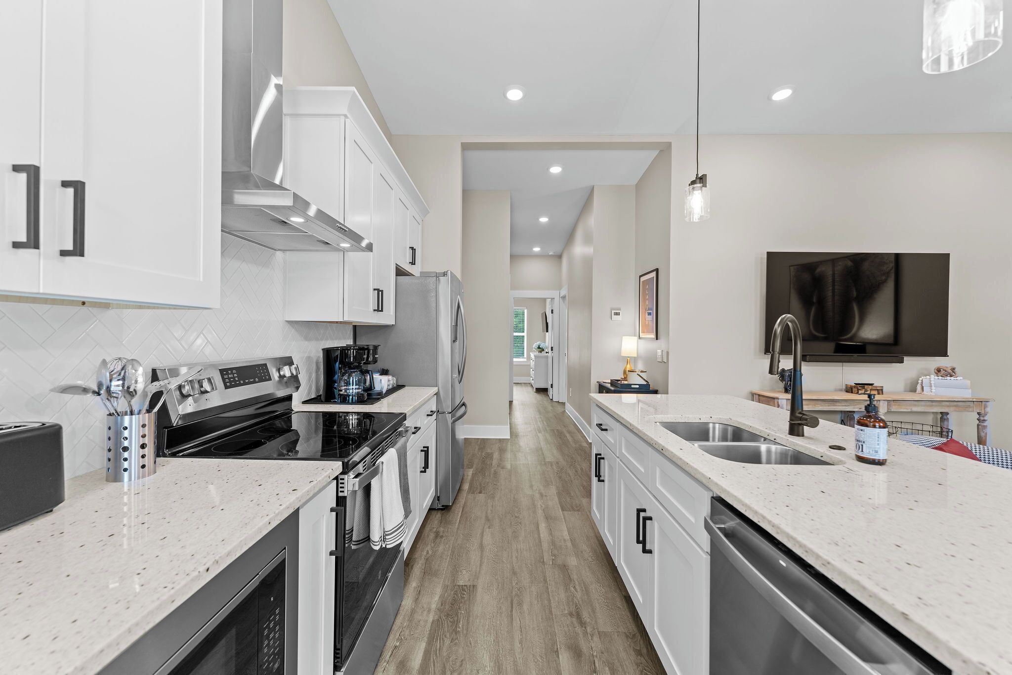 A modern kitchen with white cabinetry, stainless steel appliances, and a central island with a sink.