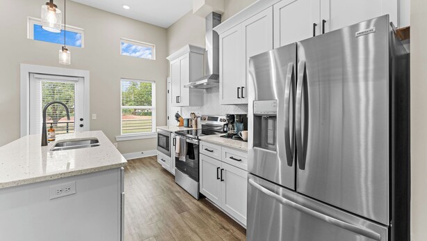 A modern kitchen with stainless steel appliances, white cabinetry, and a large island with a sink.