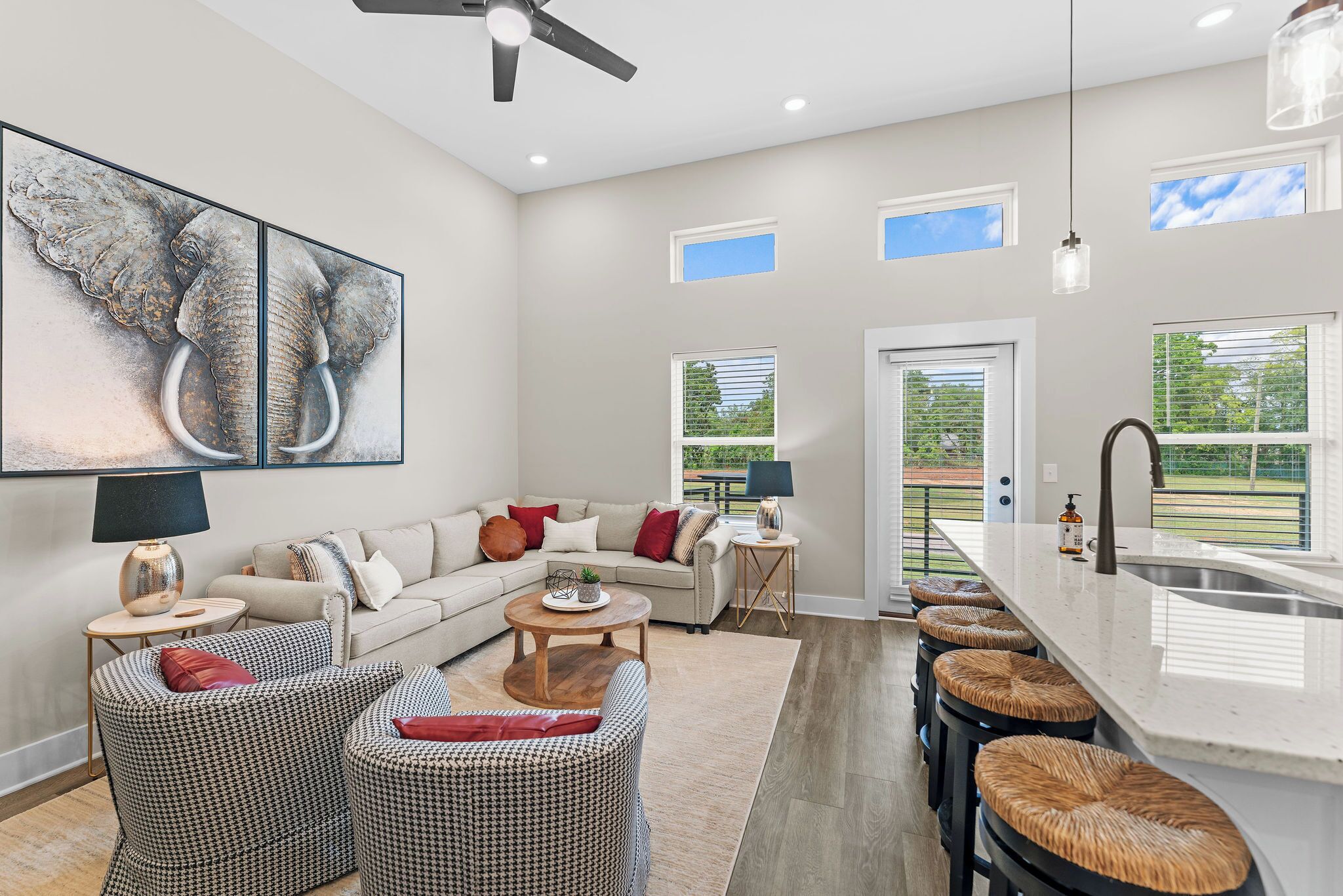 A spacious living area with a sofa, two armchairs, a coffee table, and a kitchen with a large island and bar stools.