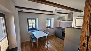 A compact kitchen with a dining area, wooden floors, and a view through the windows.