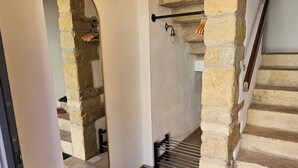 A staircase with stone walls, a black mat at the bottom, and a light fixture above.