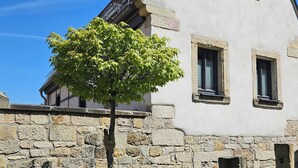 A stone building with a triangular roof and two windows.