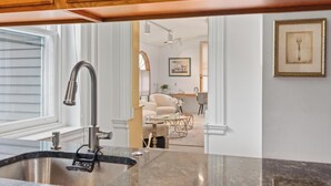 A kitchen with wooden cabinets, a stainless steel sink, and a dining area with a white chair and a glass coffee table. - Charming Luxury 2-bedroom building in lovely Allentown with AC, fitness room (Allentown)