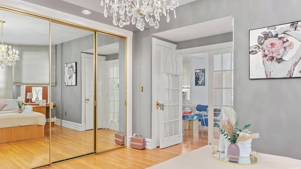 A modern bedroom with a large mirror, a chandelier, and a bedside table with a vase. - Charming Luxury 2-bedroom building in lovely Allentown with AC, fitness room (Allentown)