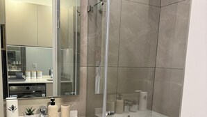 A modern bathroom with a glass-enclosed shower, a vanity with a sink, and a mirror above the counter.