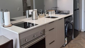 A modern kitchen with a built-in oven, a microwave, a washing machine, and a sink.