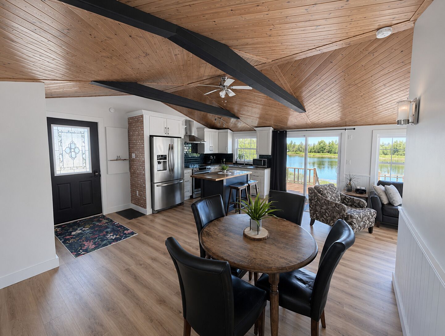 A modern kitchen with a refrigerator, stove, and island. There is a dining area with a table and chairs.