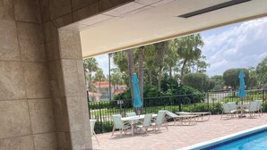 Ein Grill mit Blick auf einen Swimmingpool und eine Sitzgelegenheit im Freien.