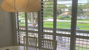 Ein Essbereich mit einem runden Tisch, Stühlen und einem großen Fenster mit Jalousien.