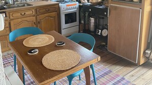 A kitchen with wooden cabinets, a stove, a sink, and a window. - Comfortable tiny house with kitchen and summer bathroom by the sea (Brem-sur-Mer)
