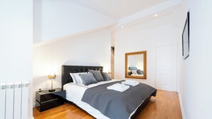 Une chambre moderne avec un grand lit, des tables de chevet, un miroir et un radiateur.