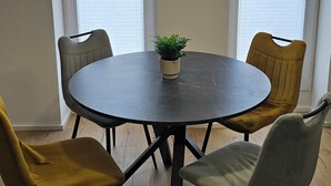 A dining area with a round table, four chairs, a potted plant, and an air conditioning unit above.