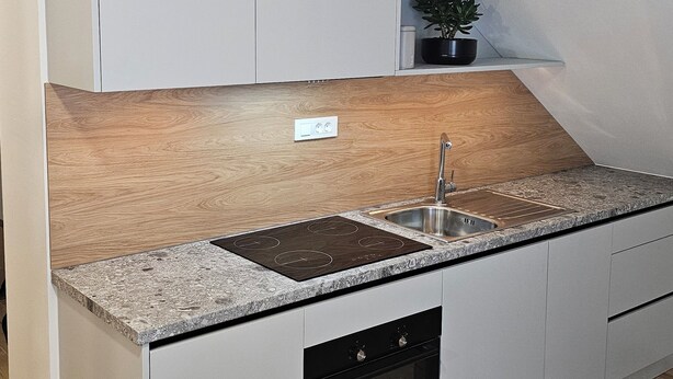 A modern kitchen with white cabinetry, a granite countertop, a built-in oven, and a sink.