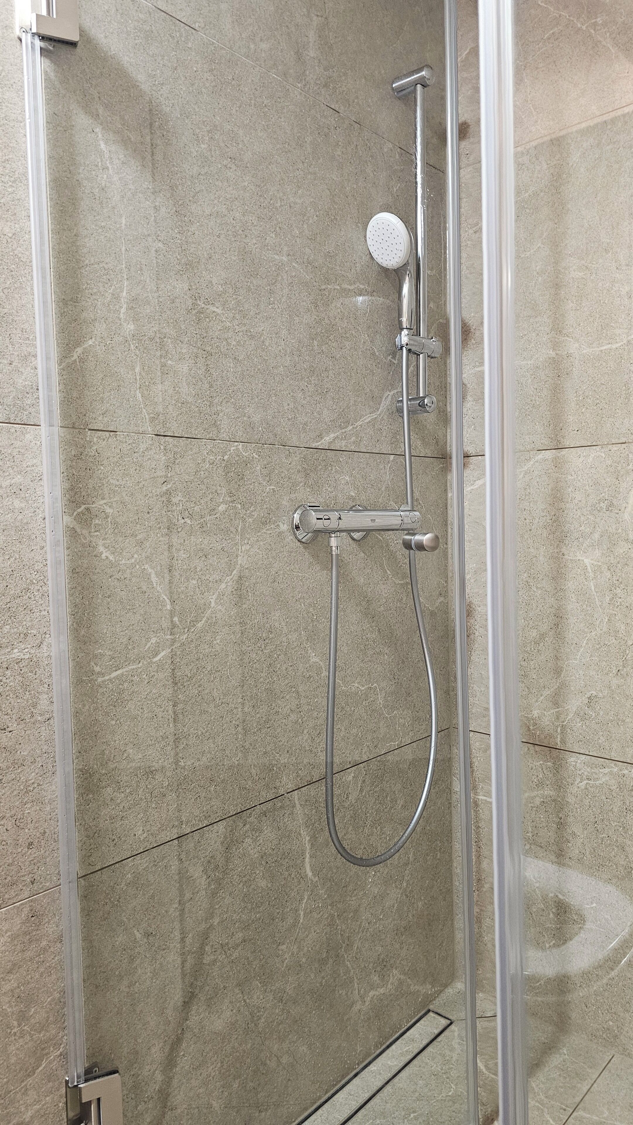 Une cabine de douche équipée d’un pommeau de douche à main et d’un pommeau de douche fixe.