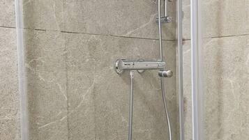 Une cabine de douche équipée d’un pommeau de douche à main et d’un pommeau de douche fixe.