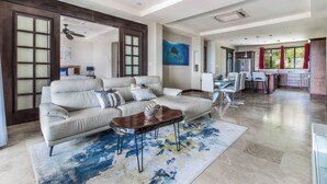 A spacious living area with a large sofa, a coffee table, and a dining area with chairs and a table.