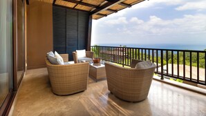 A balcony with wicker furniture, a ceiling fan, and a view of the ocean.