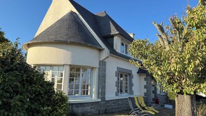 Une maison avec une façade en pierre, une grande fenêtre et une cheminée.