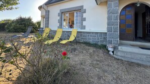 Une maison avec une façade en pierre, une grande fenêtre et une porte ornée de vitraux.