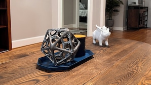 A wooden dining table with a decorative metal sculpture and a mug.