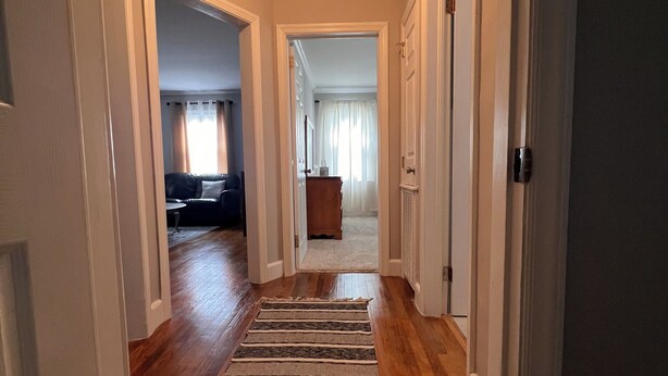 A hallway with wooden flooring and a striped rug.