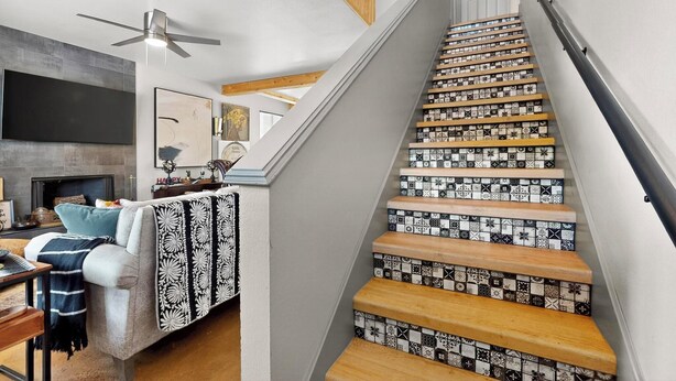 Un escalier orné de carreaux décoratifs et un salon moderne avec un canapé, une cheminée et des œuvres d’art.