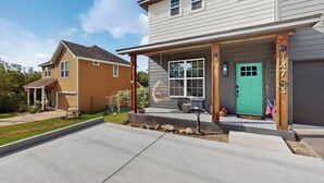 Une maison à deux étages avec un porche couvert, une porte verte et une boîte aux lettres.