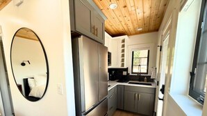 Una cucina compatta con elettrodomestici in acciaio inossidabile, soffitto in legno e un ampio specchio.