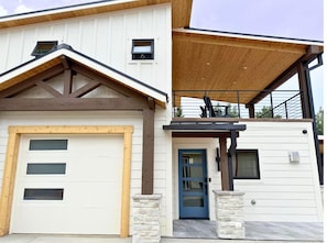 Une maison à deux étages avec un garage, une porte bleue et un patio couvert.
