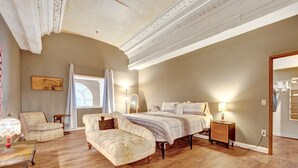Un dormitorio con una cama grande, dos sillas, una mesita de noche y un espejo.
