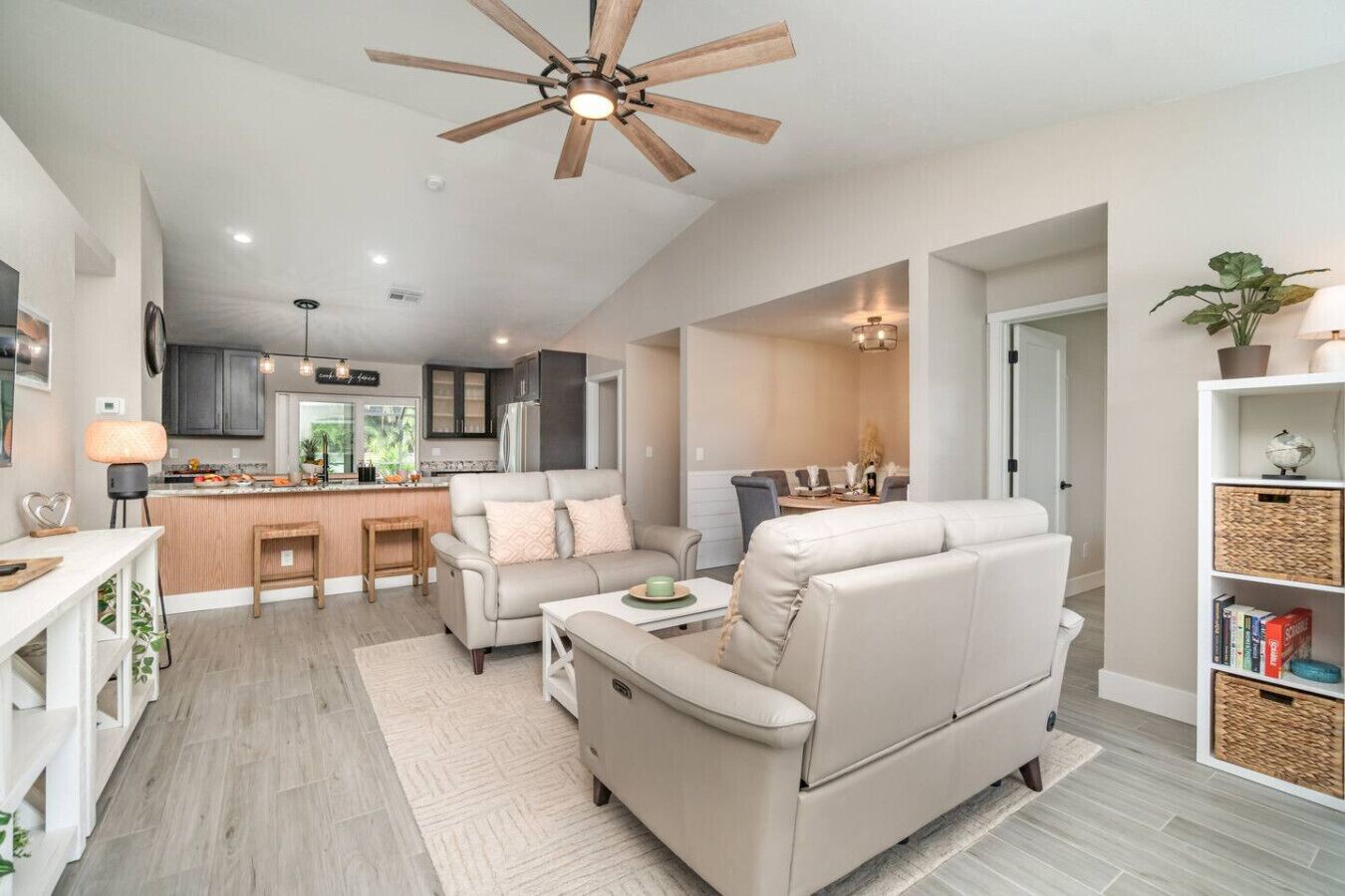 A modern living room with a sofa, coffee table, and a dining area with a kitchen in the background.