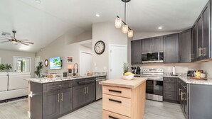 A spacious kitchen with dark cabinets, a central island, a microwave, and a stove.