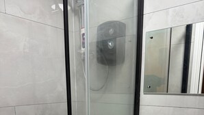 Un baño moderno con ducha de mampara de vidrio, lavabo blanco y espejo sobre el lavabo.
