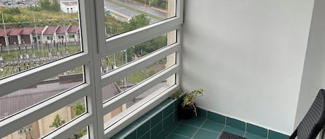 A balcony with a table and chairs, a view of a cityscape, and a potted plant.