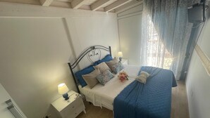 Ein Schlafzimmer mit einem Bett, Nachttischen, einer Lampe und einem Fenster mit Vorhängen.