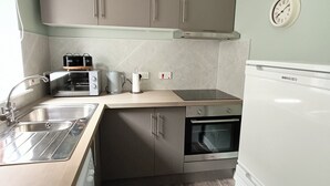 Una cocina compacta con lavamanos, tostadora, hervidor, horno y refrigerador.