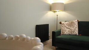 Una sala de estar moderna con un sofá verde, una lámpara blanca y un reloj en la pared.