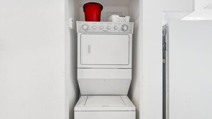 A compact laundry room with a washing machine and dryer stacked vertically. - Beachfront Condo at Beach Club - Large Balcony! (Gulf Shores)