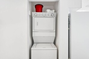 A compact laundry room with a washing machine and dryer stacked vertically. - Beachfront Condo at Beach Club - Large Balcony! (Gulf Shores)