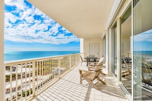 Un balcon avec vue sur l’océan, une porte et une table avec des chaises.