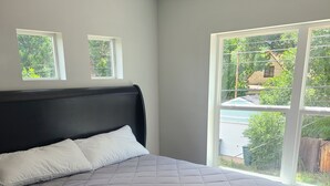 Un dormitorio con una cama grande, un cabecero y dos ventanas.