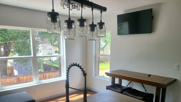 Una cocina con un lavamanos empotrado, una mesa de madera y un televisor montado en la pared.