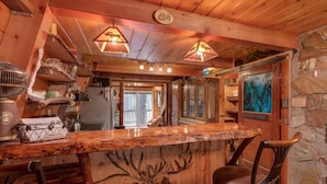 Een rustiek houten interieur met een bar, stenen muren en uitzicht op de omgeving.