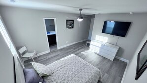 Una camera da letto moderna con un letto, una cassettiera, una TV e una ventola a soffitto.
