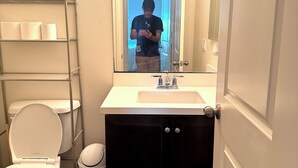 A bathroom with a toilet, sink, and mirror.