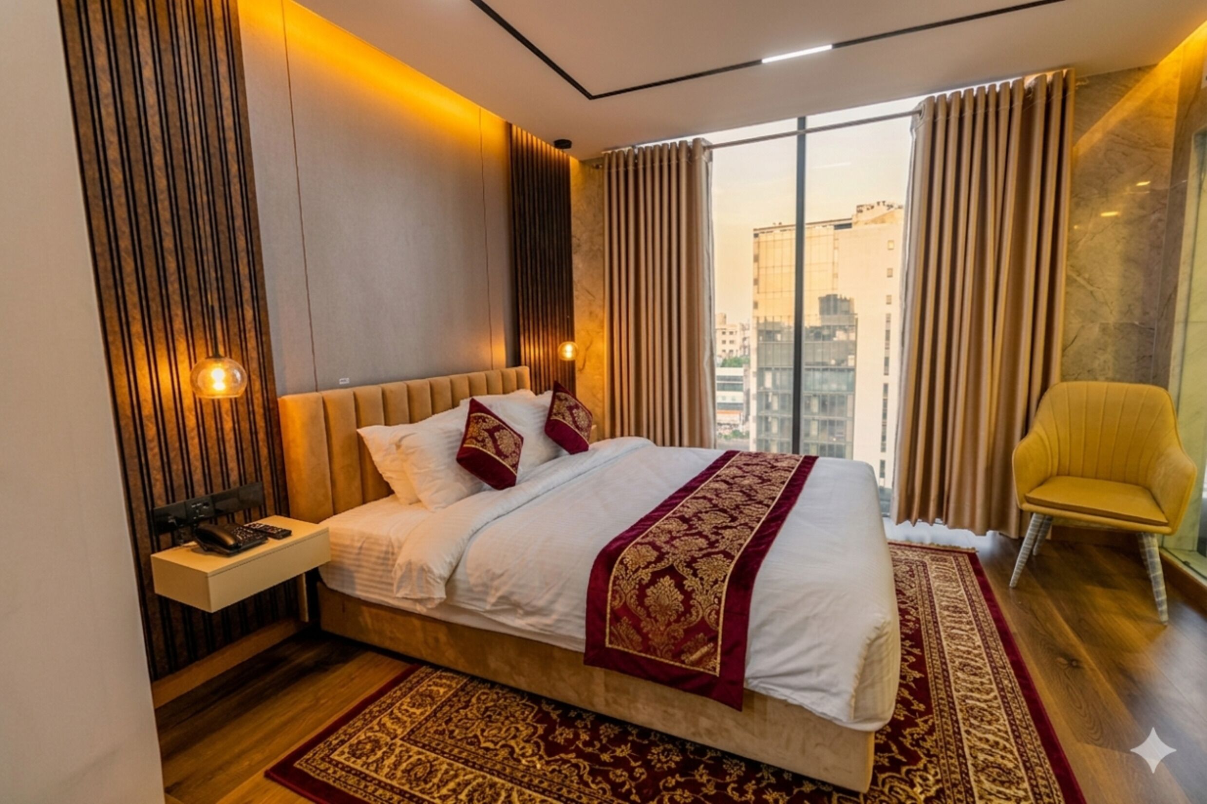 A modern hotel room with a large bed, a bedside table, a chair, and a view of the city.