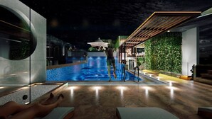 Ein moderner Innenpoolbereich mit freiem Blick auf den Pool, eine Person am Pool und eine Sitzecke mit Tischen und Stühlen.
