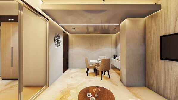 A modern, compact room with a dining area, a flat-screen TV mounted on the wall, and a wooden cabinet. - Monsoon Courtyard Luxury Hotel (Dhaka)