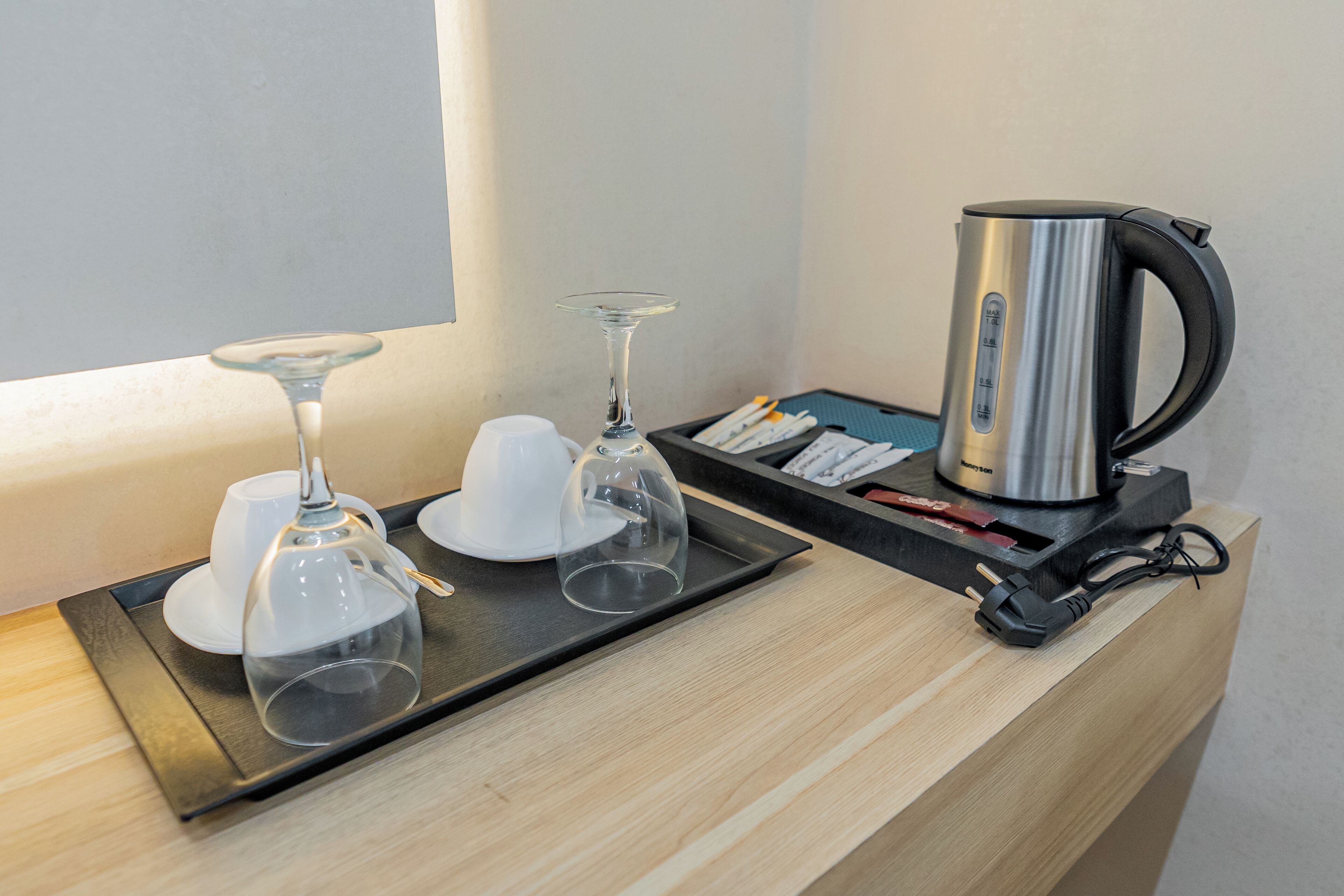 A tray with a glass, a cup, and a teapot on a wooden counter near a window.