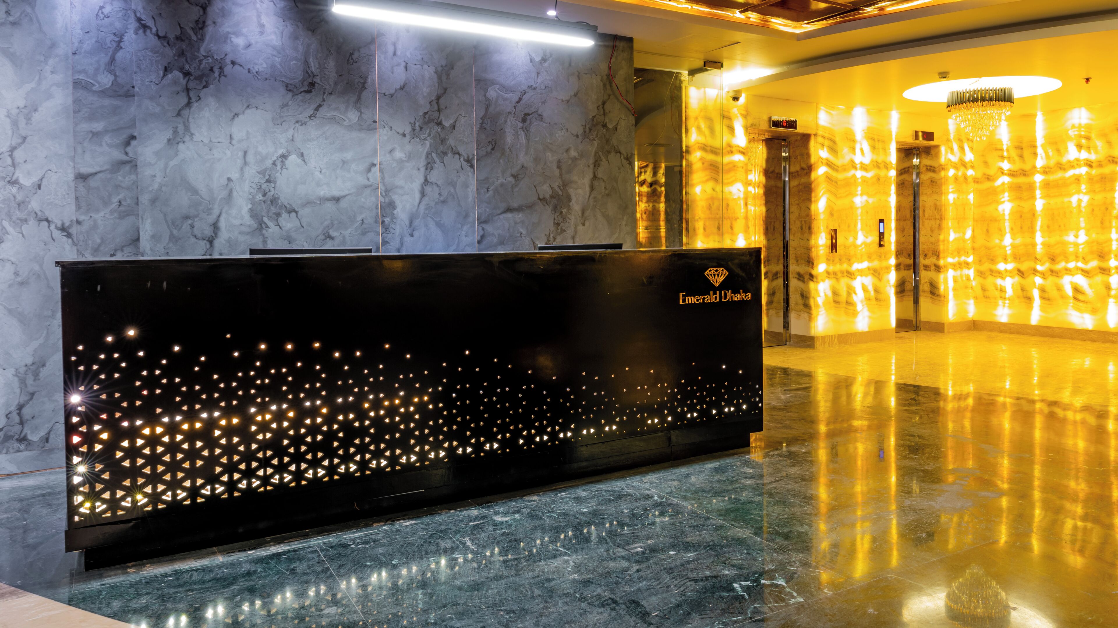 A reception desk with a marble wall and a golden light feature.